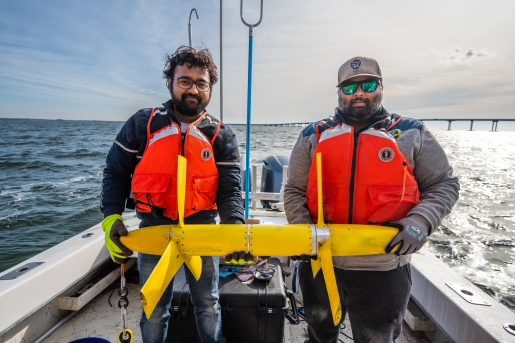 Two researchers holding a turbine on a boat